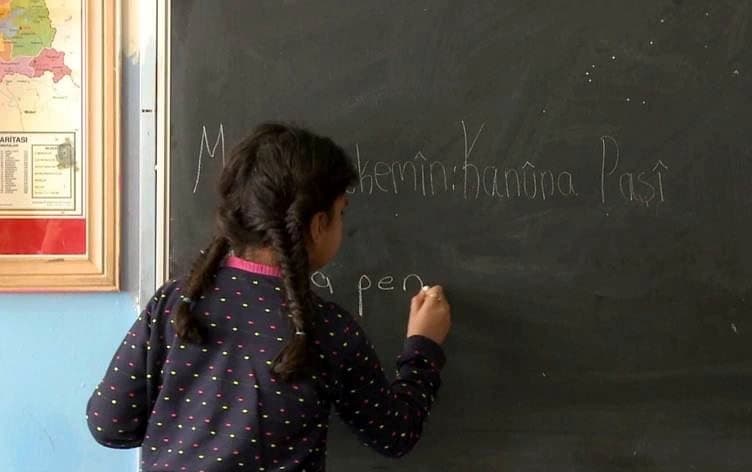 فتاة كوردية تكتب على لوحة (السبورة) باللغة الكوردية