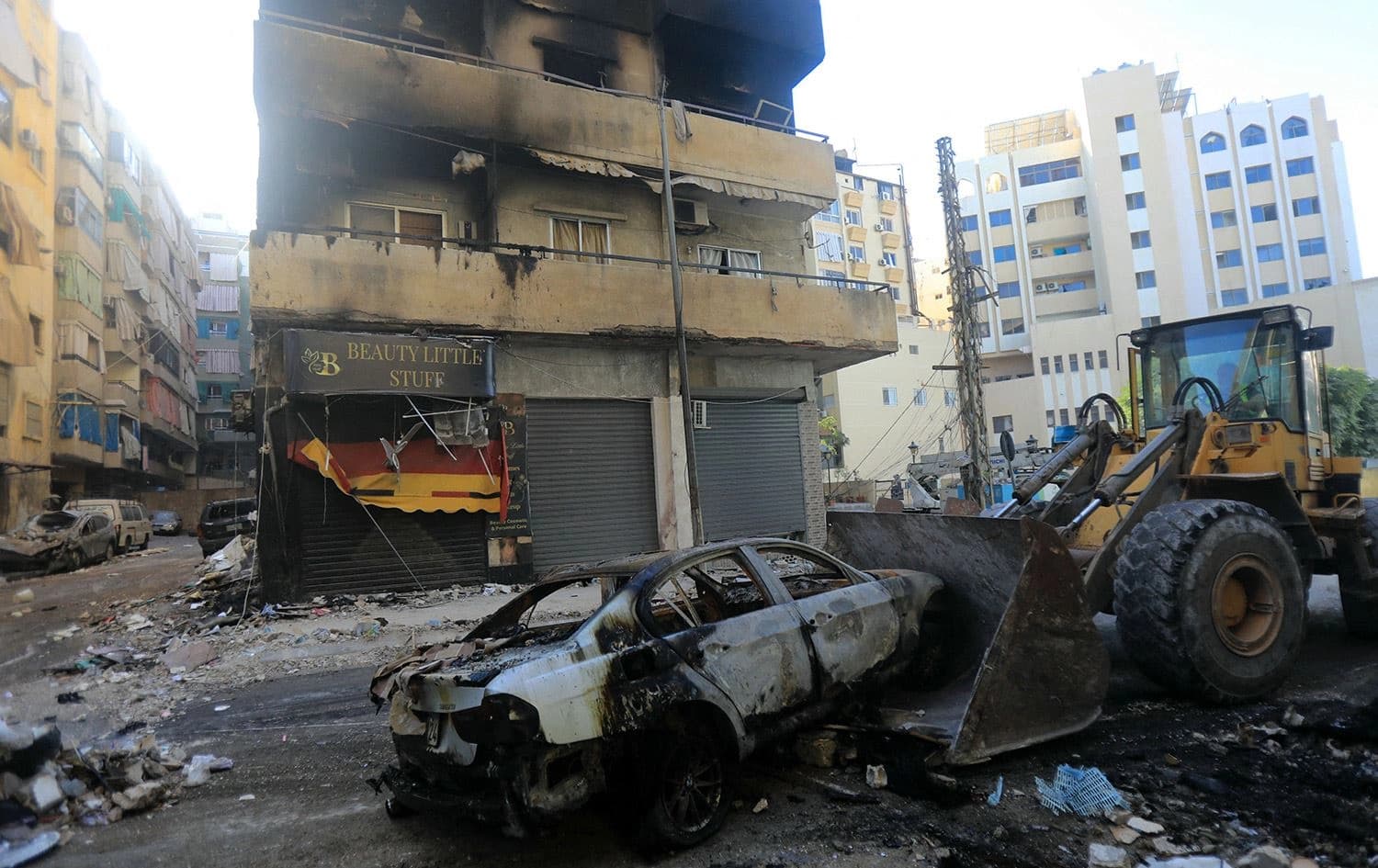 سيارة متفحمة أمام مبنى متضرر في الضاحية الجنوبية لبيروت - AFP