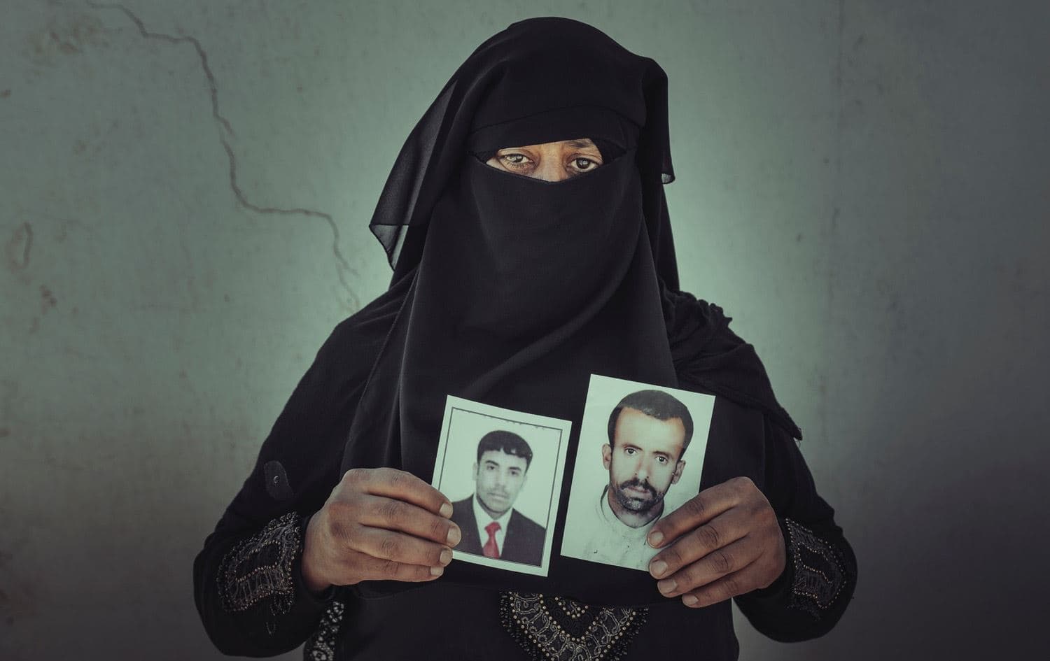 سيدة تحمل صورتين لاثنين من مفقوديها- الصليب الأحمر