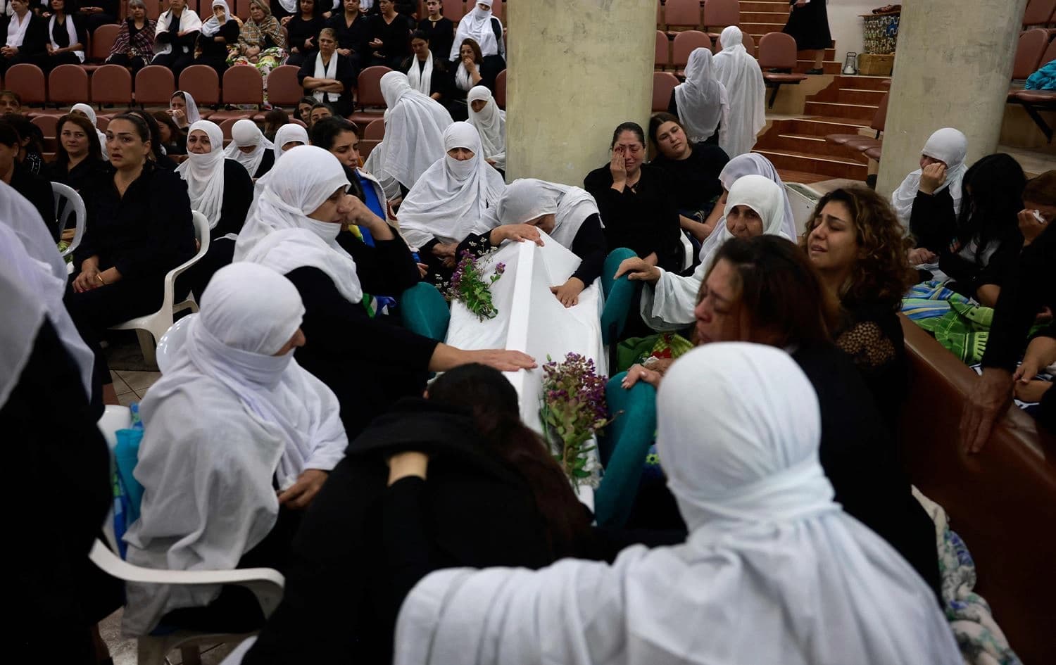 : نساء درزيات يبكين بالقرب من نعش أحد أحبائهن بعد سقوط صاروخ من لبنان على قرية مجدل شمس في منطقة الجولان