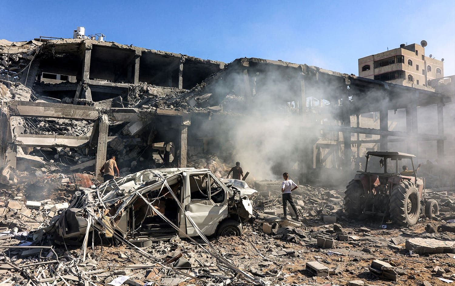 رجال يسيرون بين الأنقاض في مبنى قصفته إسرائيل في حي الشيخ رضوان شمال مدينة غزة - AFP