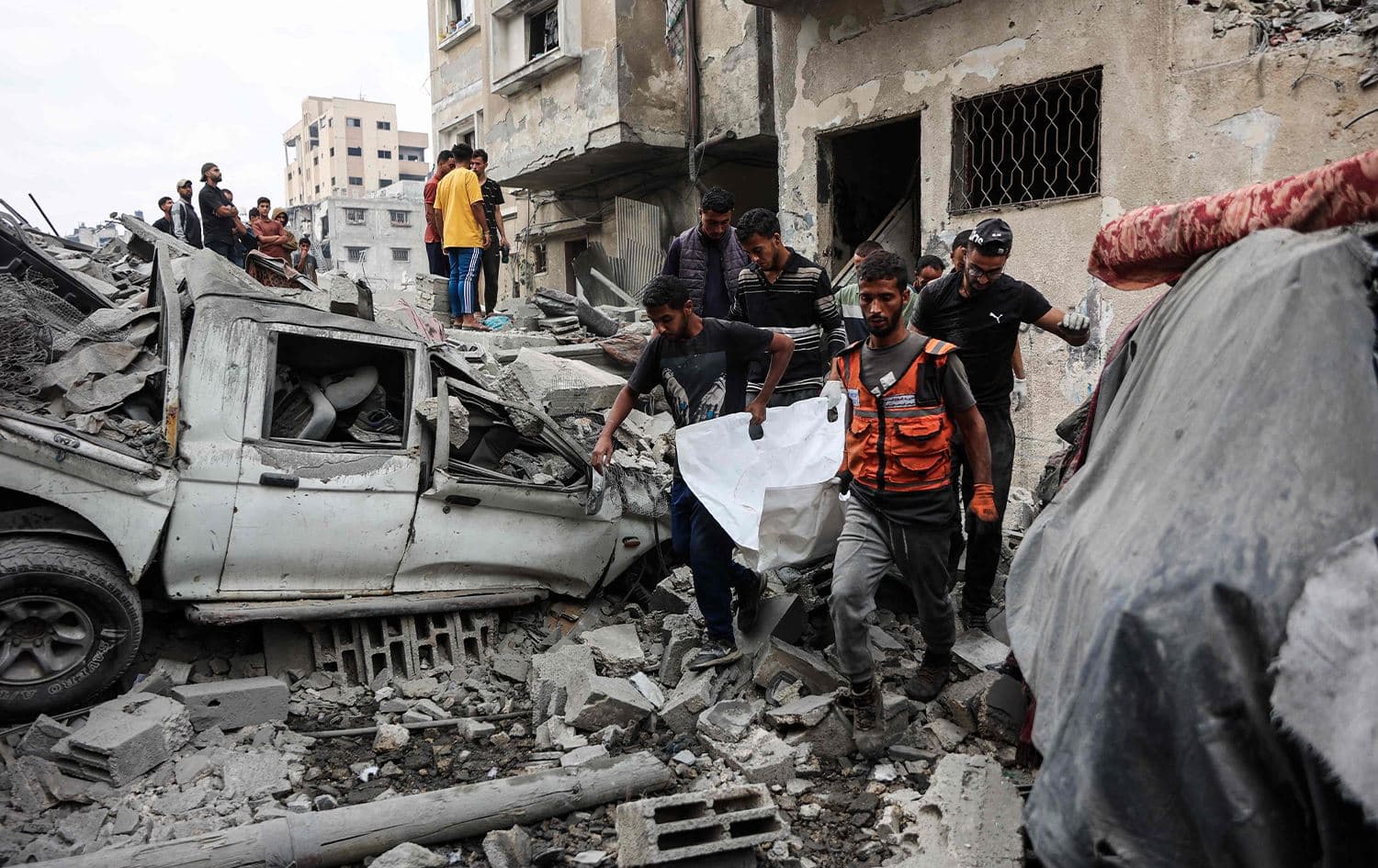 فلسطينيون ينتشلون جثة من تحت أنقاض منزل دمره هجوم إسرائيلي ليلي في غزة - AFP